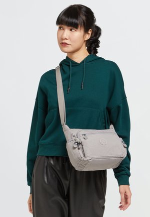 Gray crossbody bag with adjustable strap, zippered compartments, and a textured fabric finish. Features subtle branding on the front.
