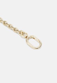 Catena in metallo tono oro con un grande fermaglio ovale dalla superficie lucida e un piccolo dettaglio inciso, che mette in risalto una texture liscia.