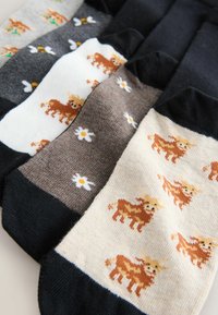 Verzameling enkelsokken in verschillende kleuren: grijs, zwart, wit en beige. Heeft patronen van koeien en madeliefjes op zacht breimateriaal.