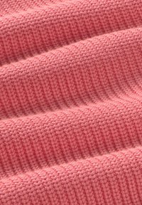 Tissu en tricot texturé et côtelé de couleur rose doux. Présente une structure chaude et légère avec des variations subtiles de couleur et de profondeur.