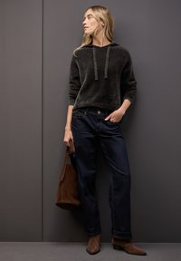 Ciemnoszara bluza z kapturem o luźnym kroju i sznurkami, zestawiona z ciemnoniebieskimi dżinsami. Uzupełniona o brązową zamszową torebkę i dopasowane buty.