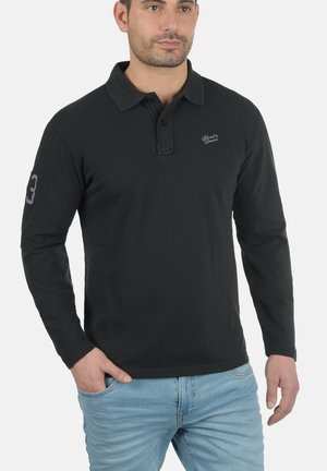 Crna polo majica dugih rukava s kragnom, s izvezenim logom na prsima i brojem 3 na rukavu. Ležeran kroj i pamučna tekstura.