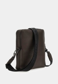 Braune, strukturierte Lederhandtasche, rechteckige Form, mit einem schwarzen Logo-Gurt und zwei Reißverschlussfächern. Kompakte und funktionale Gestaltung.