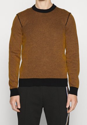 Gebreide trui in een goudbruine kleur met een gestructureerd patroon. Heeft een zwarte geribde halslijn en manchetten, een aansluitend lichaam en lange mouwen.