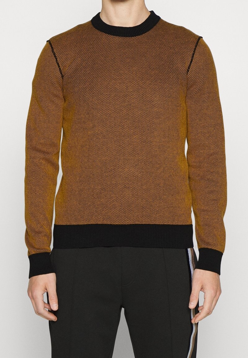 Sweter dziany w kolorze złoto-brązowym z teksturowanym wzorem. Posiada czarny prążkowany kołnierz i mankiety, dopasowaną sylwetkę oraz długie rękawy.