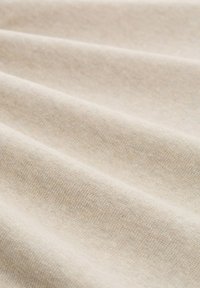 Lichtbeige stof met een zachte, gestructureerde oppervlakte, met subtiele geweven details en zachte plooien.