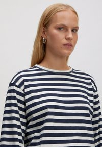 Gestreiftes Langarmshirt in Marineblau und Creme mit Rundhalsausschnitt und lockerem Schnitt. Weiches, glattes Material mit sichtbaren Nahtdetails.