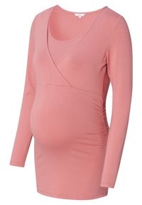 Koszulka ciążowa w miękkim różowym materiale, z przełamaną linią dekoltu, długimi rękawami i marszczeniami po bokach, które podkreślają sylwetkę brzucha.