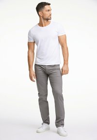Witte t-shirt met korte mouwen, gecombineerd met grijze slim-fit broek en witte sneakers, met een eenvoudig ontwerp en een gladde textuur.