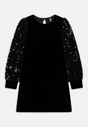 Vestido de terciopelo negro con escote redondo y mangas largas cubierto de lentejuelas negras iridiscentes, cierre trasero con botón y apertura en forma de ojo de cerradura.