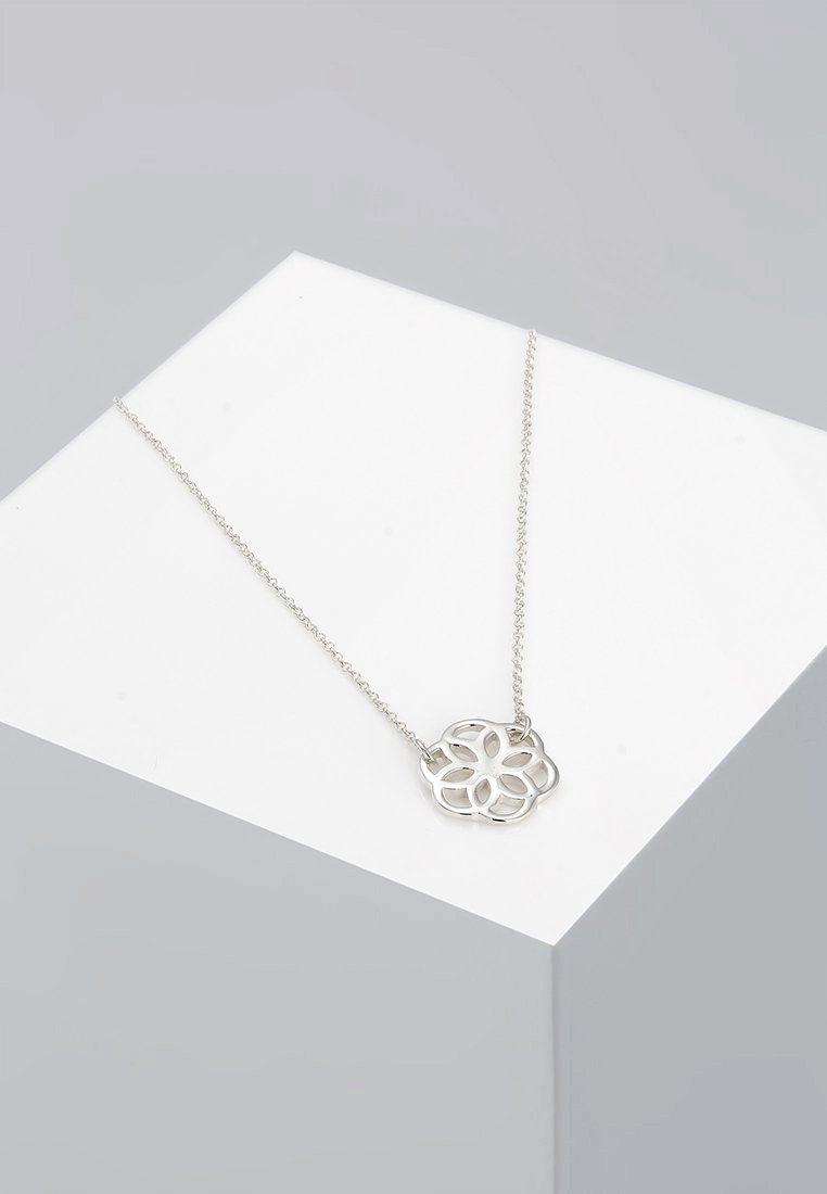Sølv halskæde med pendant i blomstermotiv, der har et intrikat udskæringsmønster, hængende fra en fin kæde.