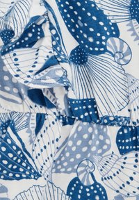 Medvilnės audinys su mėlynos ir baltos spalvos kriauklių bei lapų raštu. Papuoštas banguotais kraštais ir skirtingomis tekstūromis visame dizaino paviršiuje.