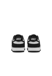 Čierno-biele tenisky z kombinácie semišu a kože, so zaoblenou špicou, plochou bielou podrážkou a výrazným brandingom "NIKE" na pätách.