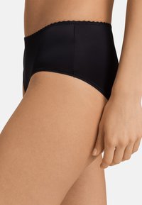 Pantaloni intimi neri a vita alta realizzati in tessuto liscio con delicate rifiniture a scallop lungo la vita e bordi elastici puliti.
