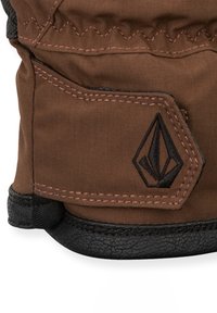 Gant en tissu marron avec des accents en cuir noir, comportant des coutures roses et un logo noir en forme de losange sur la zone du poignet.