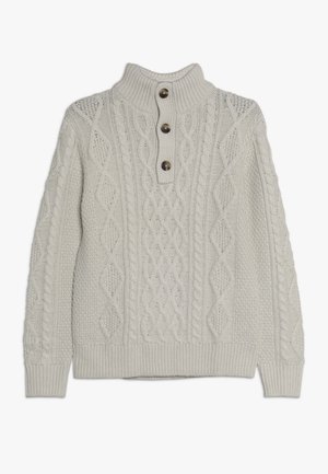 Flødefarvet kabelstrikket sweater med høj ribbet krave og tre brune knapper ned langs frontklappen.
