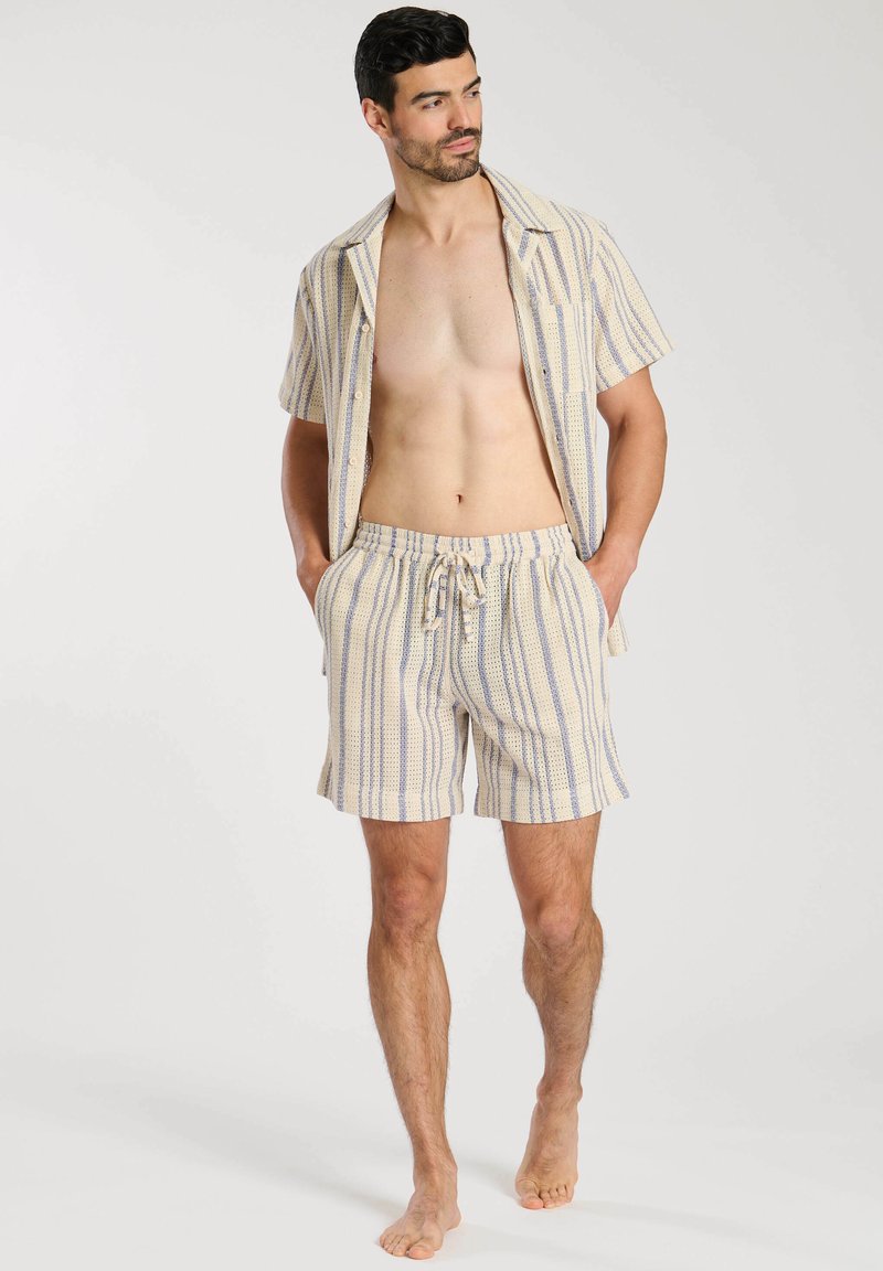 Kortärmad randig skjorta med knappar och matchande shorts i kräm, blått och gult. Lätt material, avslappnad passform, dragsko i midjan.