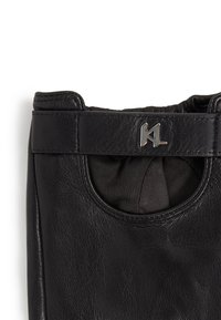 Black leather glove with a smooth texture, featuring a rounded opening and a metallic logo accent on the cuff.