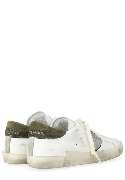 Zapatillas blancas de cuero con acentos en gamuza gris y verde olivo, cordones planos, perforaciones y una suela de goma texturizada. Presenta un detalle desgastado.