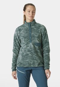 Pull-over en polaire vert à motifs avec un col zippé, comportant des snaps et une poche sur la poitrine. Texture douce et design de poids moyen.