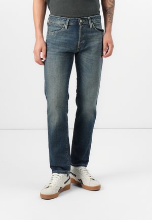 Mörkblå jeans i denim med rak benstil, blekt mönster, fem fickor och knäppning, matchat med vita sneakers.