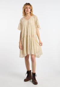 Tulipunainen beige mekko lyhyillä liehuvilla hihoilla, rypytetty vartalo, kerrostettu hame ja pehmeä rakenne, yhdistettynä ruskeisiin nauhakenkiin nilkkamittaisina.