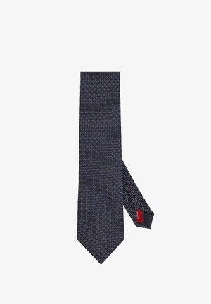 Granatowy krawat z geometrycznym wzorem w kolorze pomarańczowym i niebieskim, z czerwoną metką marki pod spodem, wykonany z gładkiej tkaniny.