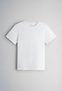 T-shirt blanc uni à manches courtes et col rond, posé à plat sur un fond gris clair.