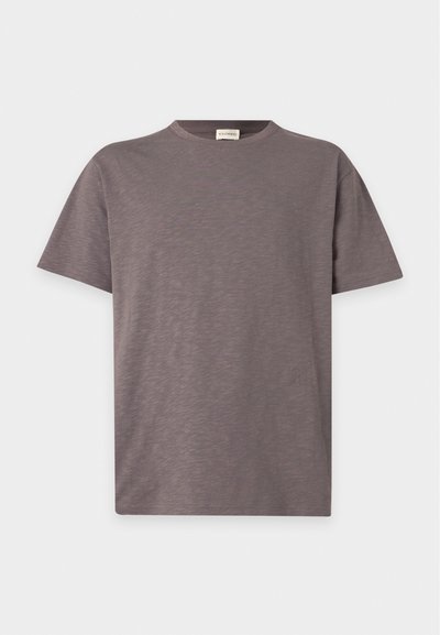 T-shirt uni à manches courtes et col rond, couleur marron atténuée avec une texture subtile et un petit logo près du bas à droite.