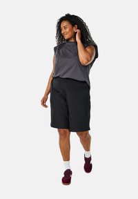 Gray short-sleeve top paired with black knee-length shorts. The footwear is burgundy sneakers with white socks. Simple and functional design.
