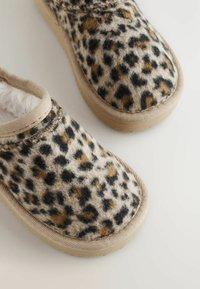 Leopárd mintás slip-on cipők, puha, textúrált felsőrésszel és bézs gumitalppal. Kényelmes bélés és a széleken varrott részletek jellemzik.