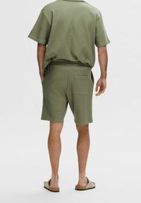 Olivgrön kortärmad skjorta och matchande shorts i texturerad tyg, med en bakficka på shortsen och en avslappnad passform.