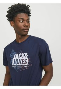 Camiseta de algodón azul marino con un gráfico blanco que presenta el texto "JACK & JONES" y un diseño de mapa de la ciudad en azul claro y rosa.