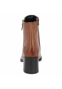 Botín de cuero marrón con cremallera lateral, tacón negro texturizado, acabado suave y logo grabado en el lateral exterior.