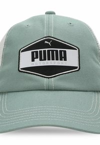 Zelena tkanina kapa sa strukturiranim dizajnom, koja sadrži crno-bijeli heksagonalni znak s natpisom "PUMA MOTORSPORT" i bijelim šavovima.
