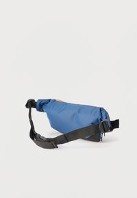 Μπλε τσαντάκι μέσης με μαύρο ρυθμιζόμενο λουράκι και αγκράφα, τοποθετημένο επίπεδα πάνω σε λευκό φόντο.