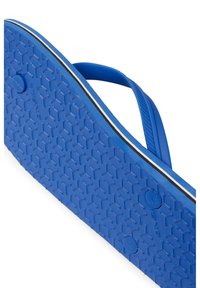 Blue flip-flop with a textured rubber sole featuring a honeycomb pattern, thin straps, and a contrasting white stripe along the edge.