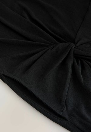 Schwarzer Stretchstoff mit einem verdrehten Knotendetail in der Mitte, mit weicher Textur und glatter Oberfläche, an den Kanten gefaltet.