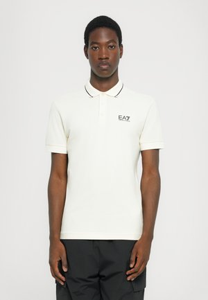 Cream polo shirt with black collar piping and EA7 logo on the left chest, made from soft cotton fabric. Classic fit with short sleeves.