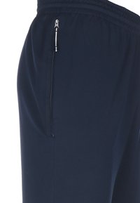 Granatowe spodnie sportowe z teksturowanej tkaniny, z zamykaną na zamek kieszenią po boku oraz elastycznym pasem dla zapewnienia wygodnego dopasowania.