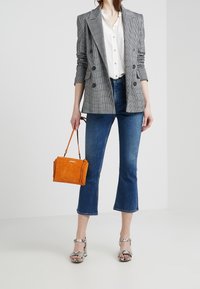 Gray plaid double-breasted blazer over a white blouse, paired with blue flared jeans, snake-print heels, and an orange suede handbag.