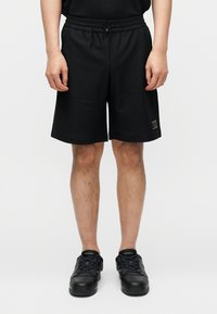 Μαύρο δίχτυ σορτς με ελαστική μέση, μήκος μέχρι τη μέση του μηρού, με διακριτικό υφασμάτινο μοτίβο και μικρό λογότυπο ως διακοσμητικό στοιχείο.