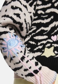 Gestrickter Pullover mit schwarz-beigem Animal-Print. Mit bunten, bestickten Augen- und Herzmotiven, gerippten Bündchen und pinken Akzenten.
