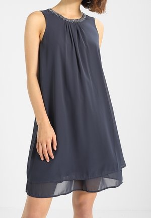 Robe sans manches gris foncé avec un corsage plissé et un col orné de perles, présentant un superposé fluide et légèrement transparent.