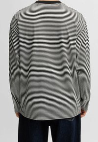 Langarmshirt in Schwarz-weiß gestreift, aus weichem Material gefertigt. Verfügt über einen Rundhalsausschnitt und eine lässige Passform mit geradem Saum.
