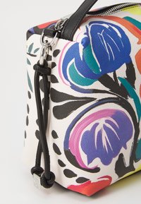 Borsa colorata con motivo floreale, in canvas bianco testurizzato, con dettagli neri e una tracolla staccabile, dotata di una chiusura superiore a zip.