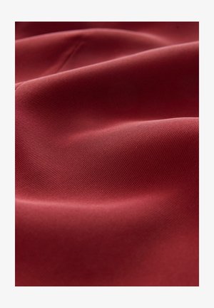 Tissu texturé d'un rouge profond avec une surface lisse, présentant des nervures subtiles et de légères plis qui créent un drapé doux.