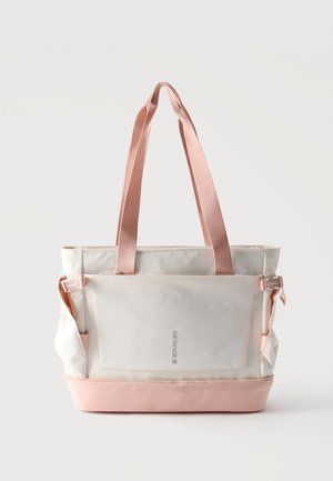 Sac cabas crème et rose pâle avec bandoulières réglables, poche avant et compartiment inférieur zippé, marqué "Stanley" à l'avant.