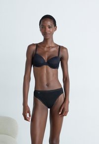 Black bra and matching bikini bottoms made of smooth fabric. The bra features thin straps and a subtle lace trim along the edges.