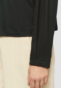 Zwarte lange mouw top van gladde stof, met een eenvoudig ontwerp, rechte snit en een schone zoom, gecombineerd met lichtbeige gestructureerde broeken.